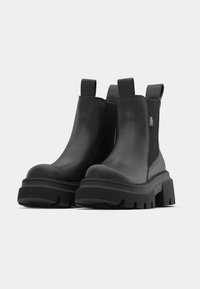 Čierne členkové topánky z hladkej kože s elastickými bočnými panelmi, hrubou gumovou podrážkou a pútkami pre ľahké obúvanie.