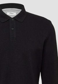 Zwarte langemouwen poloshirt gemaakt van textuurstof, met een klassieke kraag, een twee-knopen sluiting en een subtiel logo op de borst.
