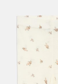 Knähöga strumpor i en ljus krämfärg med ett blommönster som har små rosa och lila blommor samt gröna inslag på ett mjukt, texturerat material.