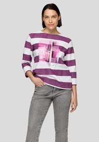 Langärmliges Hemd mit lila und weißen Streifen, mit einem pinken Grafikelement auf der Vorderseite. Der Stoff hat ein strukturiertes Aussehen.