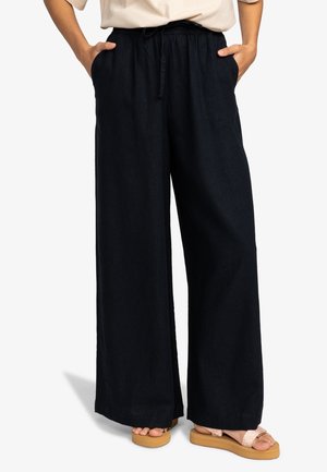 Pantalon à jambes larges en tissu bleu marine foncé, doté d'une taille élastique avec cordon de serrage, de poches latérales et d'une coupe décontractée. Surface texturée.