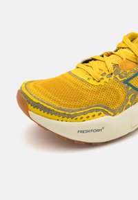 Scarpa da corsa gialla con tomaia in mesh, design testurizzato, accenti grigi e soletta in gomma. Presenta il marchio "FRESH FOAM" sul lato.