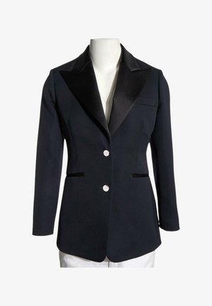 Blazer negro hecho a medida con solapas pico de satén, dos botones blancos y bolsillos de ojal delanteros en un torso de maniquí blanco.