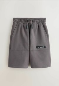 Pantaloni scurți gri, până la mijlocul coapsei, confecționați dintr-un material moale, cu talie elastică. Au două buzunare frontale și un patch cu logo pe lateral.