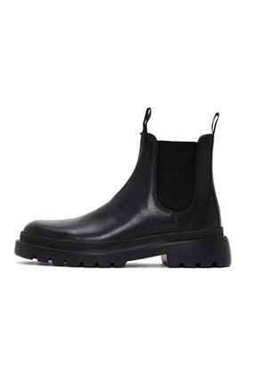 Black leather Chelsea boot with elastic side panels, pull tabs, and a chunky rubber sole featuring textured tread. Classic ankle-height design.