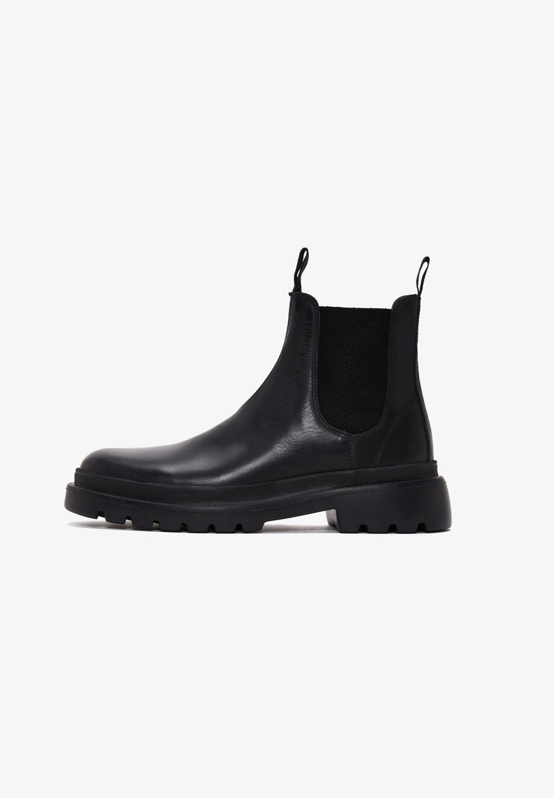 Bottines Chelsea en cuir noir avec des panneaux élastiques sur les côtés, des languettes de tirage et une semelle en caoutchouc épaisse avec un motif texturé. Design classique à hauteur de cheville.