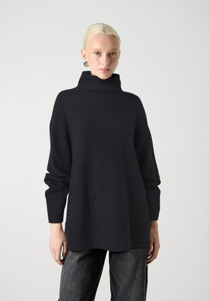 Σκοτώδη ναυτικό μπλουζάκι oversized με ψηλό γιακά, ριμπ μανσέτες και στρίφωμα, φτιαγμένο από μαλακό πλεκτό υλικό. Ορατή λεπτή υφή.