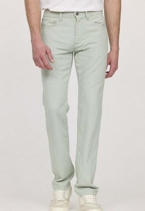 Jean vert clair, coupe ajustée, en mélange de coton, conception à cinq poches, fermeture par boutons, associé à des baskets blanches.