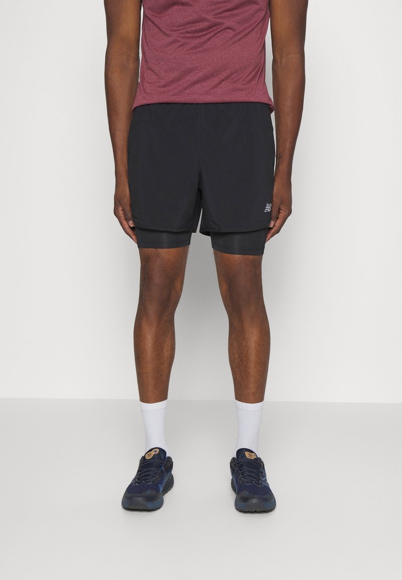 Schwarze Sportshorts mit integrierten Kompressionsshorts darunter, kombiniert mit einem bordeauxfarbenen kurzärmligen Shirt und marineblauen Laufschuhen.