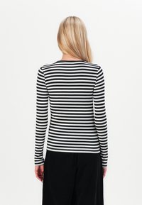 Black and white striped long-sleeve shirt, fitted design, round neckline, featuring a ribbed texture and contrasting cuffs.