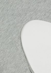 Šedá bavlněná tkanina s hladkou texturou má velký výřez a plastové patentky podél okraje.