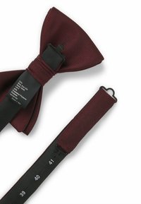 Verstellbare dunkelrote und schwarz gestreifte vorgebundene Fliege mit einem Stoffetikett, das die Zusammensetzung aus Seide und Polyester zeigt.