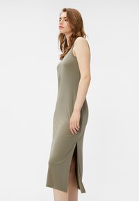 Olivengrünes, ärmelloses Maxikleid aus glattem Stoff mit einem seitlichen Schlitz. Das Design ist tailliert und endet auf Wadenhöhe.