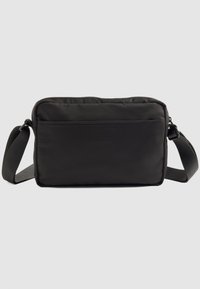 Borsa a tracolla nera rettangolare compatta con tasca frontale e tracolla regolabile in tessuto su sfondo neutro.