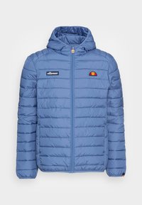 Vadderad blå hujacka med dragkedja framtill, med horisontell sömnad, en broderad logotyp på vänster bröst och elastiska ärmslut.