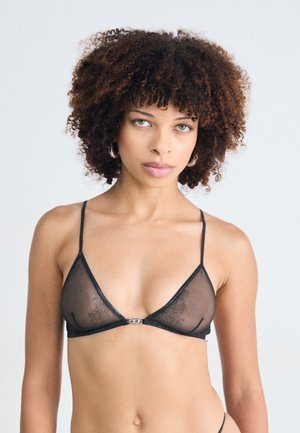 Zwarte doorschijnende bralette met een driehoekig ontwerp, dunne bandjes en een klein detail van zilver hardware aan de voorkant. Gladde textuur.