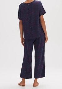 Lichtgewicht marineblauwe outfit van stof met een top met korte mouwen en wijde broekspijpen, met een meerkleurig gestreept patroon en een knoopdetail aan de achterkant.