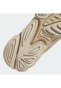 Sole béžové Adidas tenisky s texturovanými, oválnými gumovými gripy a vyraženým logem Adidas blízko středu.