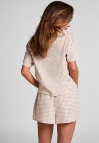 Geruite korte set in zacht beige en wit. T-shirt met korte mouwen en een relaxte pasvorm, gecombineerd met bijpassende shorts. Lichtgewicht stof.