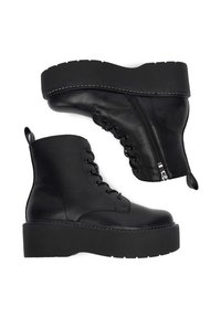 Czarne platformowe botki sięgające kostki, wykonane ze skóry, z przodem zapinanym na sznurowadła, bocznym zamkiem błyskawicznym oraz teksturowanym gumowym podeszewką z podniesionymi krawędziami.