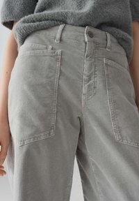 Pantaloni in corduroy grigi con gamba ampia, dotati di tasche frontali, una vita cucita e un motivo di tessuto texture.