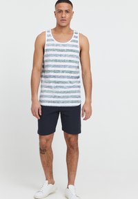 Herre tanktop med vandrette blå og grønne striber, lavet af letvægtsstof. Kombination med mørkeblå shorts og hvide sneakers.