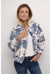 Quiltad bomberjacka i off-white med blå botanisk tryck, med rund krage, tryckknappar och elastiska ärmslut och nederkant.