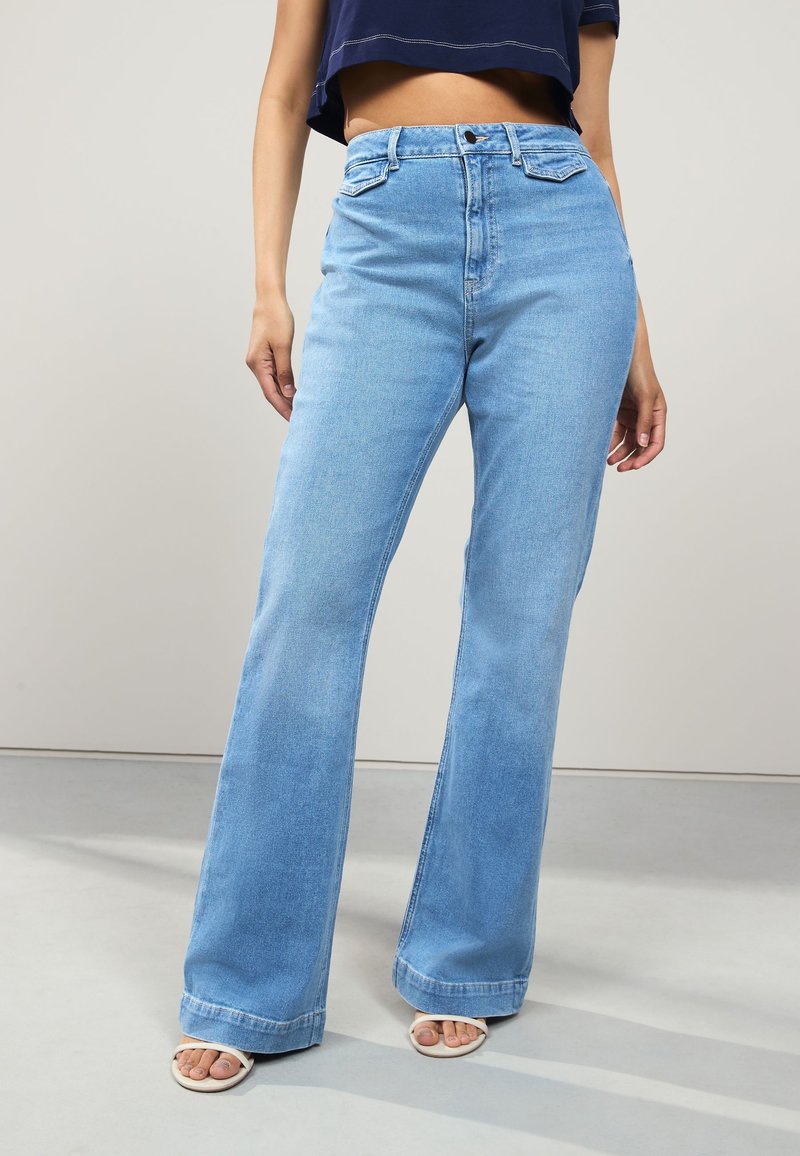 Jean évasé taille haute bleu clair en denim, présentant un design classique à cinq poches et un ourlet net.