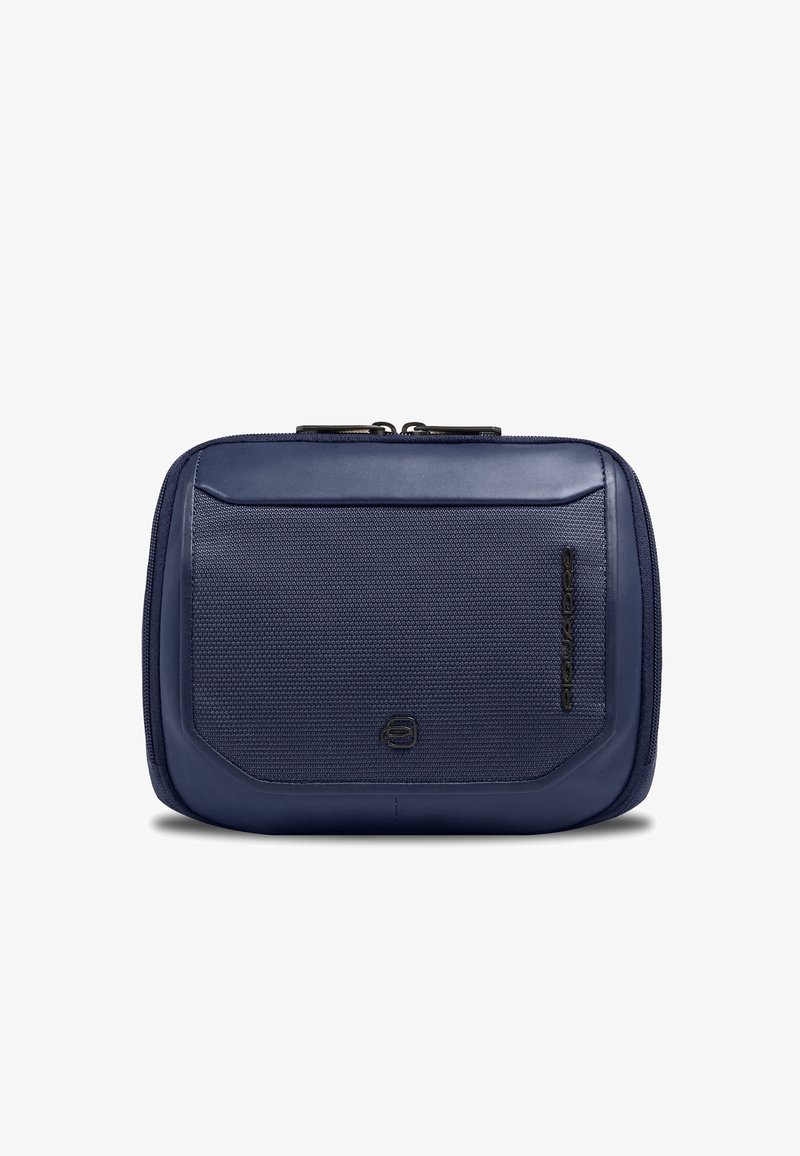 Pochette de voyage compacte bleu marine avec panneau avant texturé, fermeture éclair sur le dessus et logo de marque noir discret sur les parties inférieure et latérale.