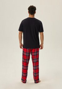 Granatowa koszulka T-shirt z krótkim rękawem w połączeniu z czerwonymi spodniami piżamowymi w kratę z niebieskimi i czarnymi liniami; luźny krój, materiał bawełniany.