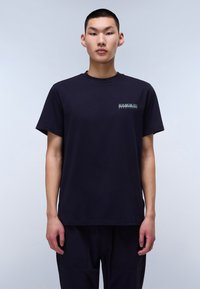 Mørkeblå bomulds t-shirt med korte ærmer og rund hals. Har et grafisk logo i kontrasterende farver på brystet. Enkel design.
