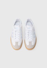 Λευκά αθλητικά παπούτσια με ανοιχτό μπλε λεπτομέρειες, γκρι σουέντ μύτη, λαστιχένια σόλα σε φυσικό χρώμα και κλασικό σχέδιο με τρεις ρίγες.