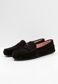 Schwarze Wildleder-Loafer zeichnen sich durch eine glatte Textur, eine abgerundete Zehenpartie und ein dekoratives Ziernähdetail auf dem Obermaterial aus. Das Innenfutter ist in Rosa gehalten.