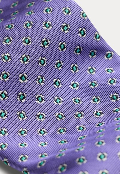 Μωβ ύφασμα με διαγώνια ραβδωτή υφή και επαναλαμβανόμενο σχέδιο μικρών πράσινων και λευκών κεντημένων εξαγώνων.