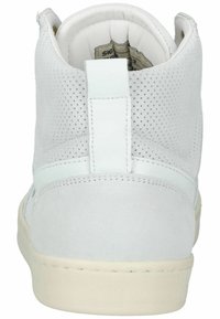 Vit högtoppsneaker med mocka och perforerad textur, cirkulär logga och platt gummisula. Bakre flik har en vertikal rand.