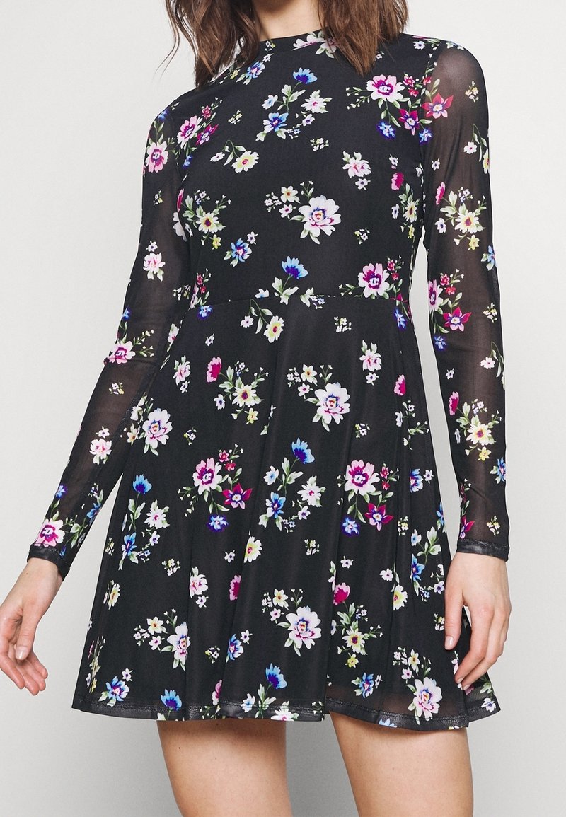 Vestido negro de manga larga, con un patrón floral en rosa, blanco y azul. Confeccionado en tela ligera, con un diseño acampanado en el dobladillo.