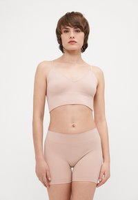 Ljusrosa ribbad bralette med tunna band och matchande sömlösa boyshorts. Mjukt tyg med en slät textur. Enkel kort design.