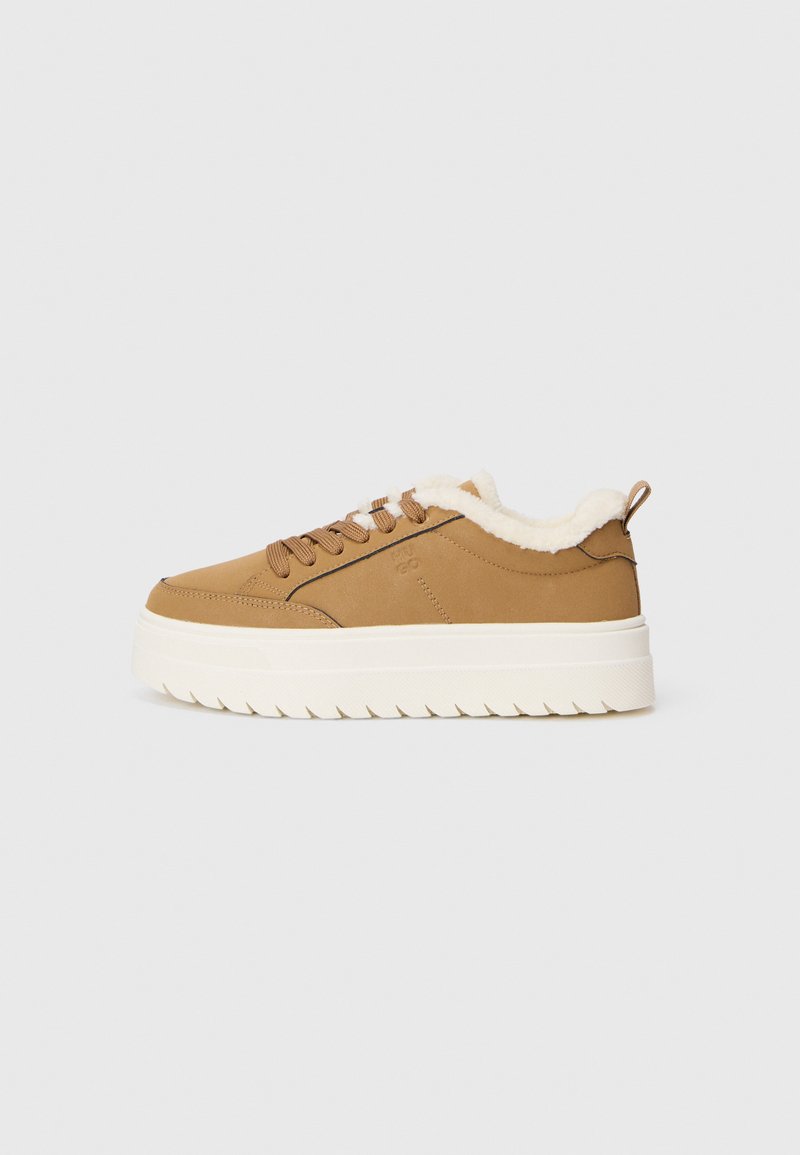 Brown leather sneaker with fluffy white lining, rounded toe, and thick white ridged sole. Features brown laces and a small back tab.