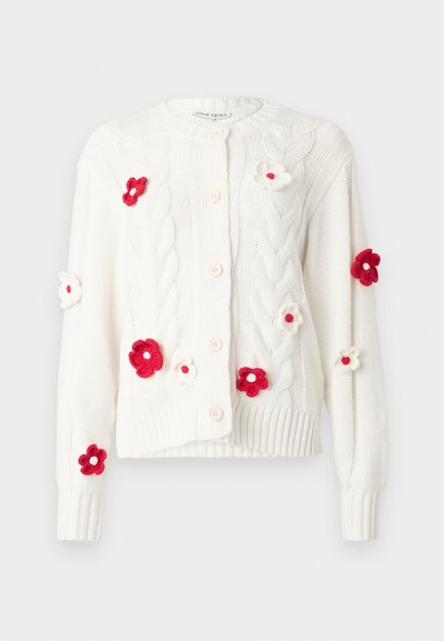 Hvit strikket cardigan med kabelmønster, rund hals og rosa knapper. Dekorert med røde og hvite blomsterapplikasjoner på forsiden.