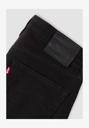 Schwarze Levi's Jeans gefaltet, mit sichtbarer Gesäßtasche mit rotem Levi's-Label und schwarzem Leder-Levi's Markenpatch über der Tasche.