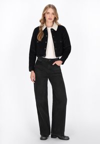 Mustat corduroy cropped -takki, jossa on kerma väri kauluksessa, yhdistettynä korkeavyötäröisiin mustiin leveälahkeisiin housuihin ja mustiin nilkkureihin. Teksturoitu pinta.
