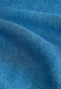 Dziļa zila denim auduma, ar gludu tekstūru un diogonālām aušanas rakstzīmēm. Krāsa ir konsekventa bez lielām izmaiņām.