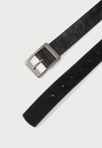 Must nahast vöö siledapinnalise tekstuuriga, metallist pandlaga ja mitme auguga reguleerimiseks. Rihmad on lamedad ja sirgete servadega.