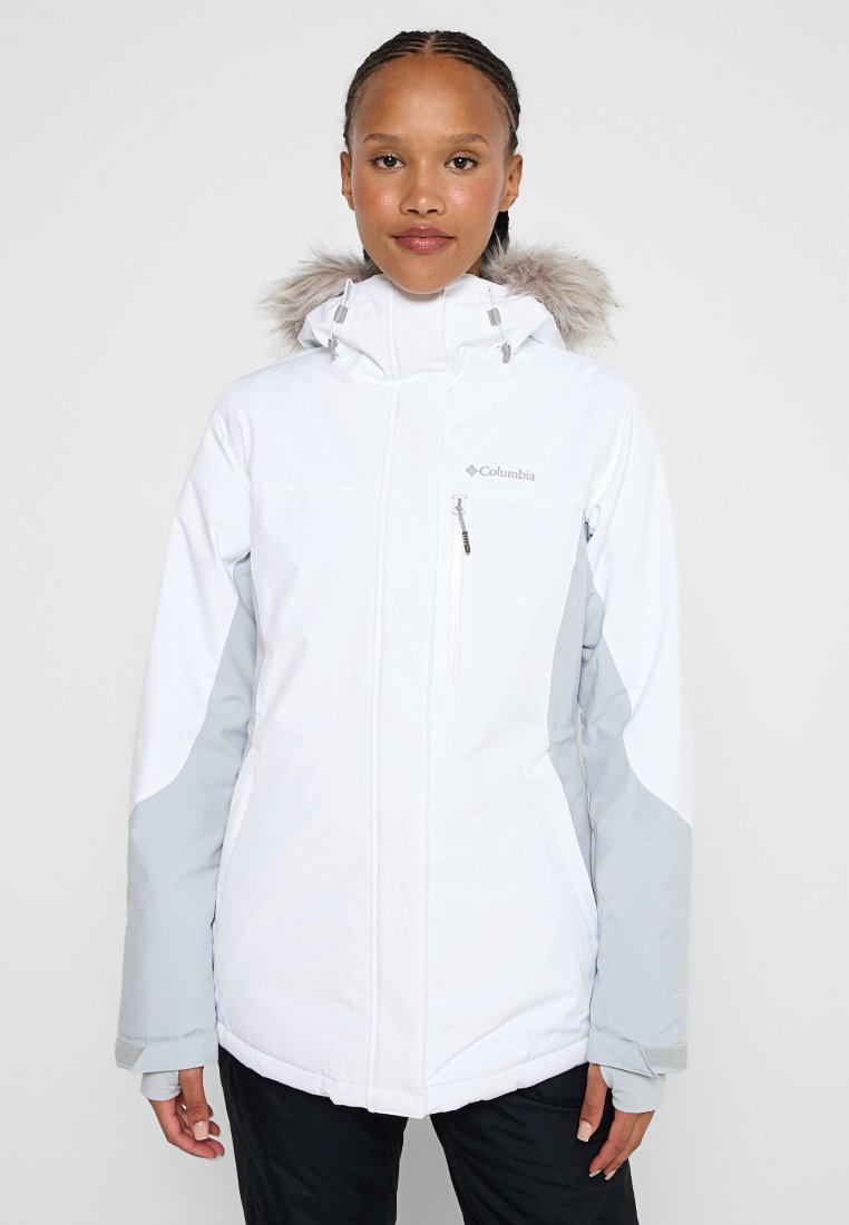 Weiße Columbia-Jacke mit einem von Pelz gefütterten Kapuze, grauen Akzenten und einer mit Reißverschluss versehenen Brusttasche; zeichnet sich durch ein schlankes Design und wasserdichtes Material aus.