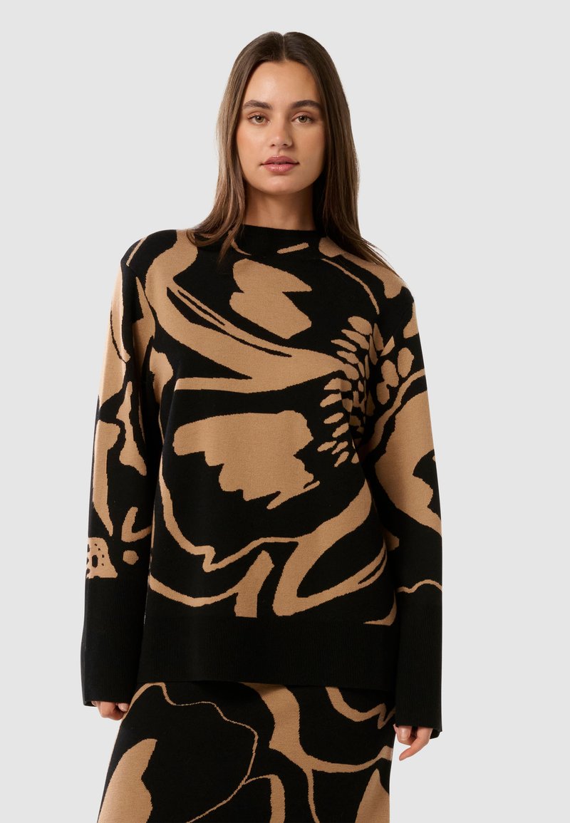 Stickad tröja med ett abstrakt blommönster i beige på en svart bakgrund, med långa ärmar och rund halsringning.