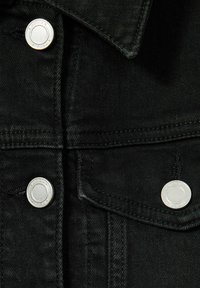 Černá džínovina má stříbrné kovové knoflíky, špičatý límec a dvojité švy. Textura je hladká s mírným leskem.