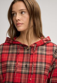 Maglione con cappuccio a scacchi rossi e neri, con bottoni sul davanti, cordini e un tessuto testurizzato, caratterizzato da una vestibilità rilassata e un rivestimento morbido.