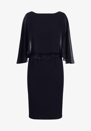 Robe noire avec une cape fluide et transparente par-dessus, des détails en dentelle à la taille et une jupe ajustée. Texture lisse et silhouette élégante.
