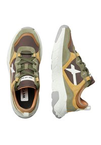 Sportskor i en blandning av grön, brun och tan mocka samt syntetiska material. Anmärkningsvärt vitt stjärnlogotyp, tjock struktur på sulan och vadderad krage.