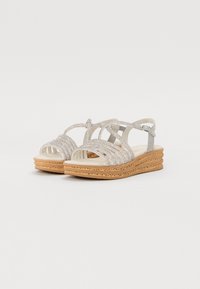 Silver strappy sandals featuring a textured wedge sole and smooth platform. The straps have a glitter finish and adjustable ankle buckle.